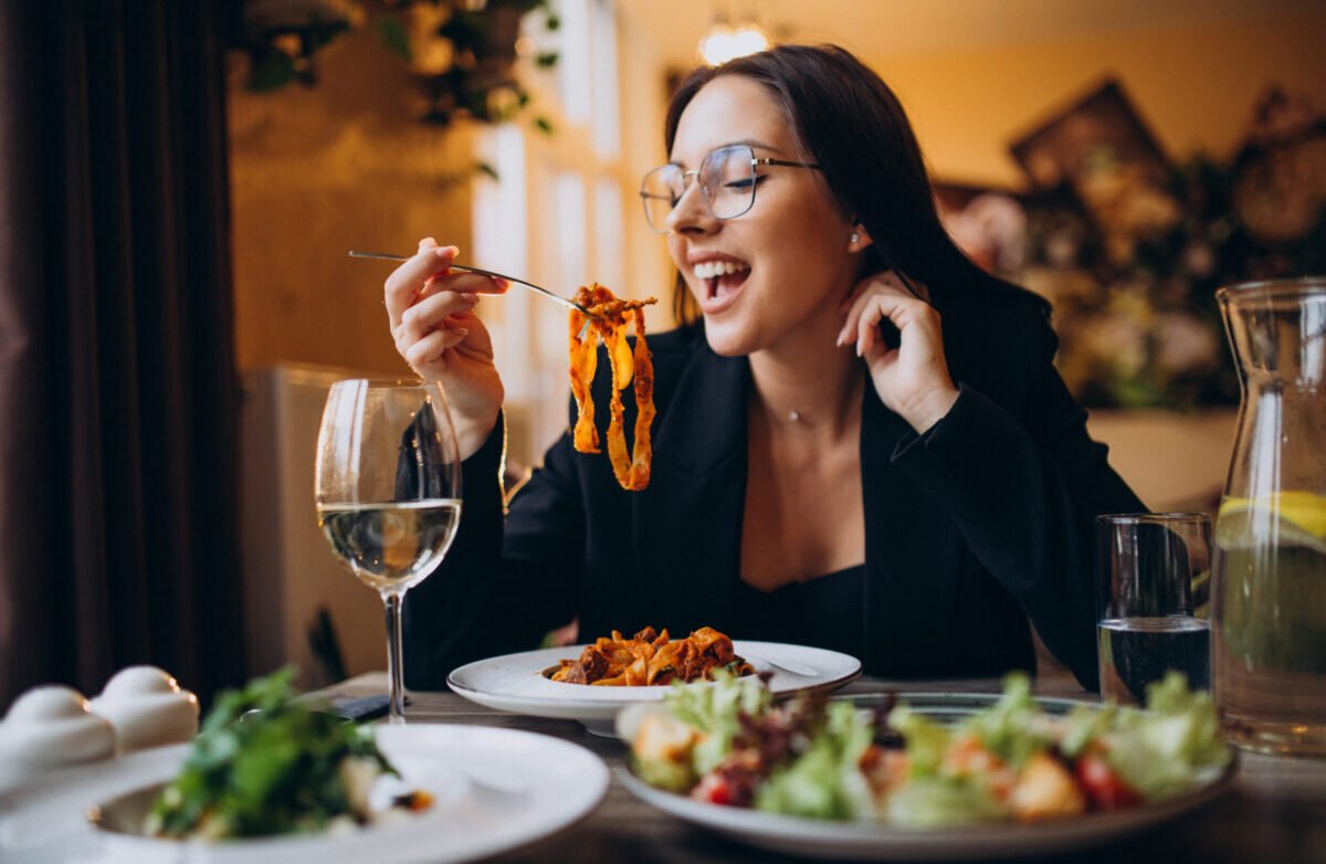 young woman eating pasta in a cafe